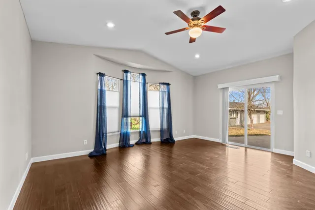 a view of an empty room with window and wooden floor
