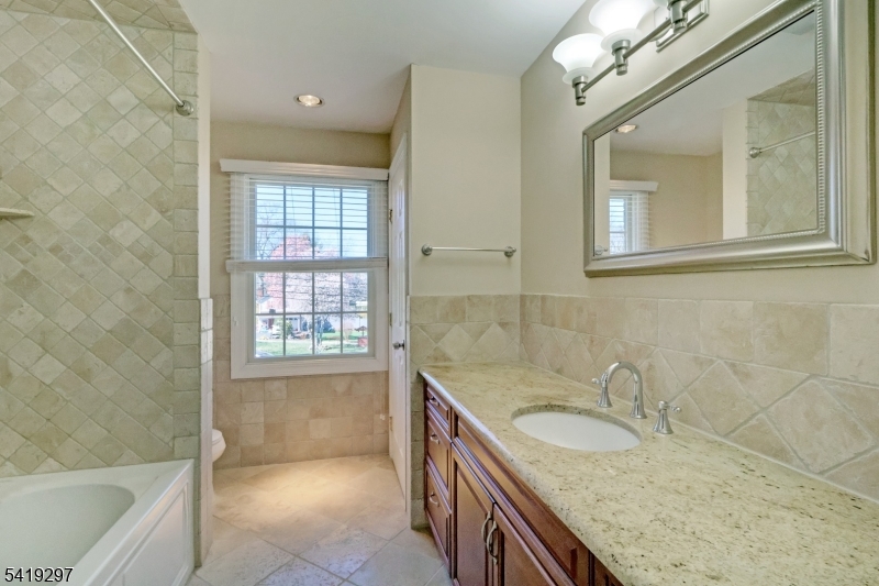 24 Pine Brook Road Montville, NJ 07082 - Photo 19 of 27 a bathroom with a granite countertop sink a mirror a bathtub and next to a window