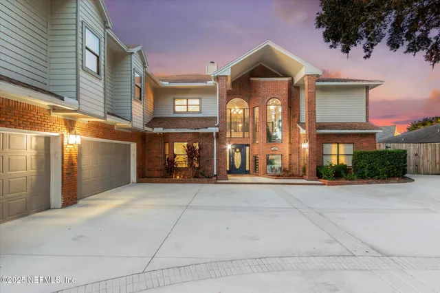 a front view of a building with lots of trees and plants