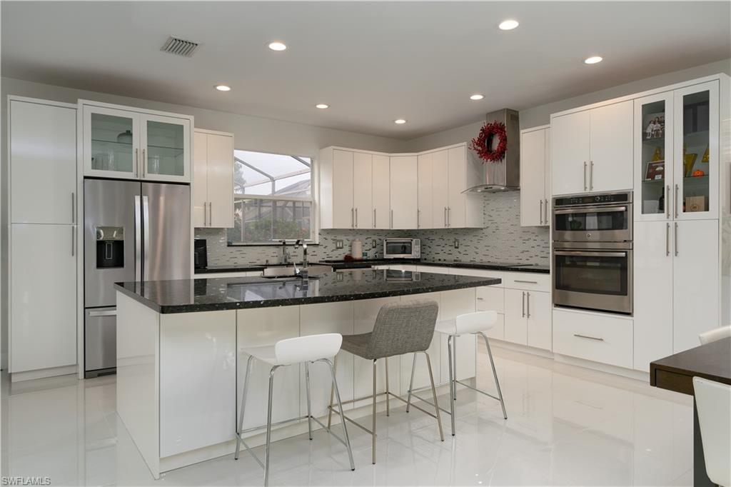 a kitchen with stainless steel appliances granite countertop a refrigerator and a stove top oven