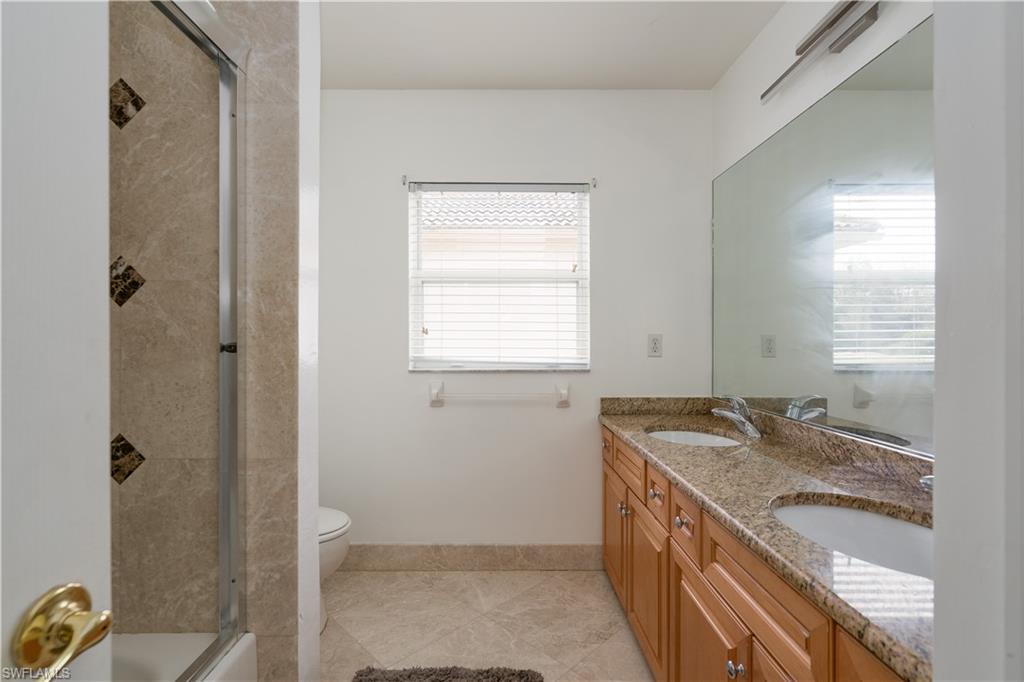 8271 Laurel Lakes Way Naples, FL 34119 - Photo 22 of 36 a bathroom with a granite countertop sink a mirror and a shower
