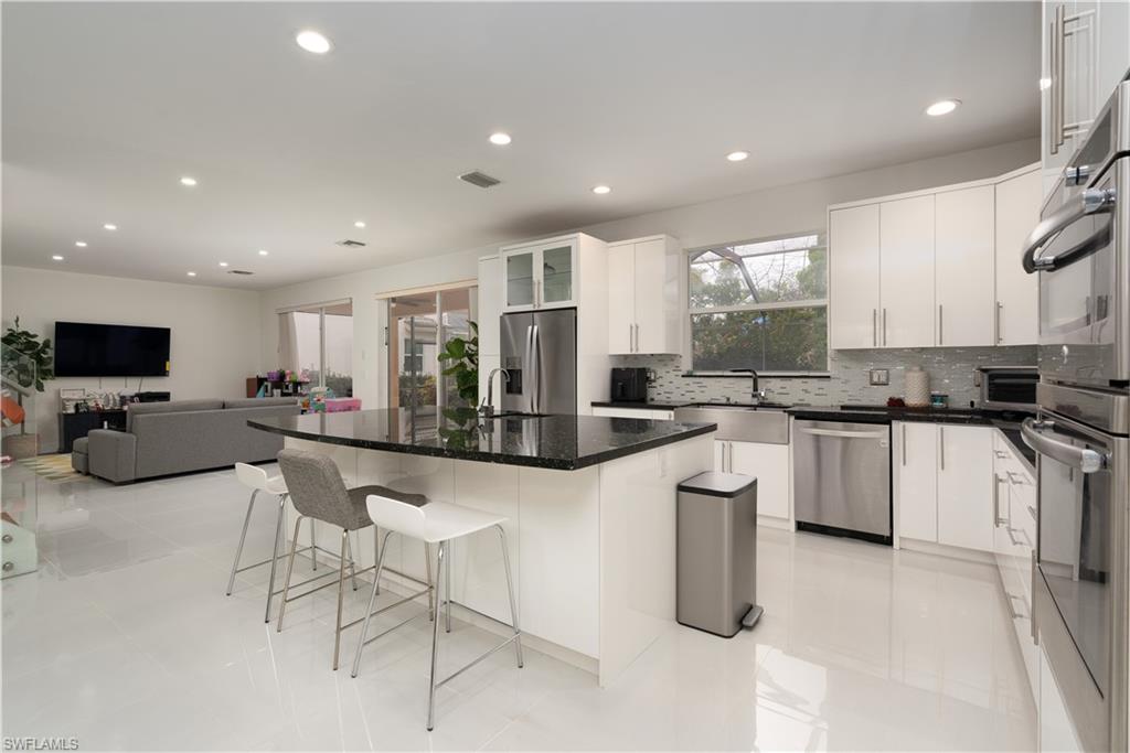 8271 Laurel Lakes Way Naples, FL 34119 - Photo 7 of 36 a kitchen with counter top space cabinets and stainless steel appliances