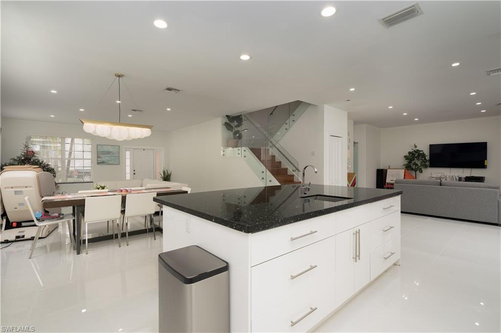 8271 Laurel Lakes Way Naples, FL 34119 - Photo 8 of 36 a kitchen with a sink and a stove top oven with wooden floor