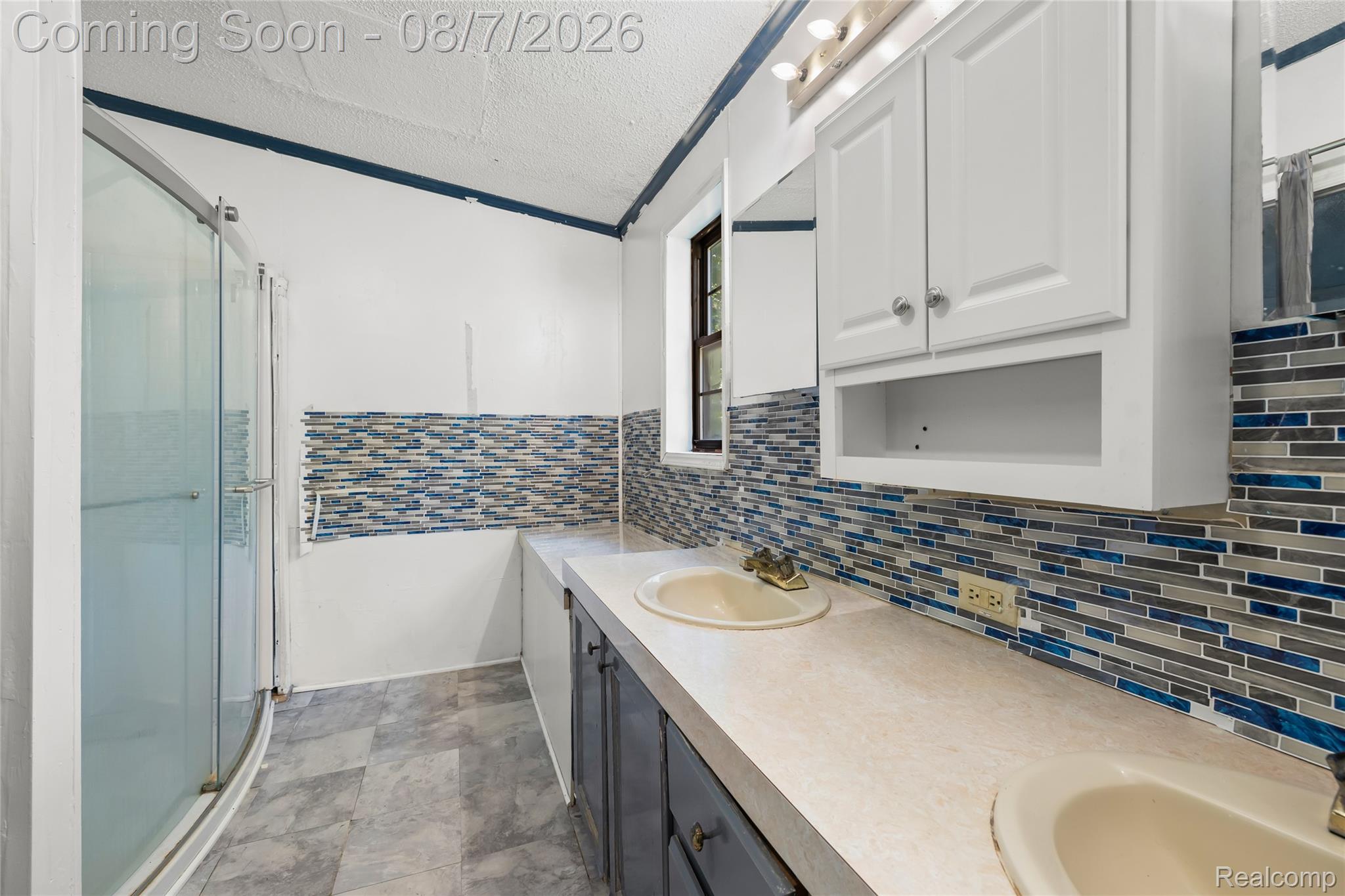 9940 Bunton Road Willis, MI 48191 - Photo 26 of 26 Bathroom with a glass-enclosed shower, dual vanity sinks, and a mosaic tile backsplash