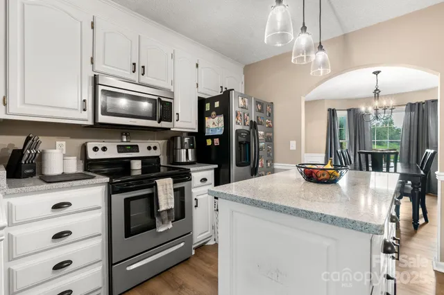 a kitchen with stainless steel appliances granite countertop a sink a stove and cabinets