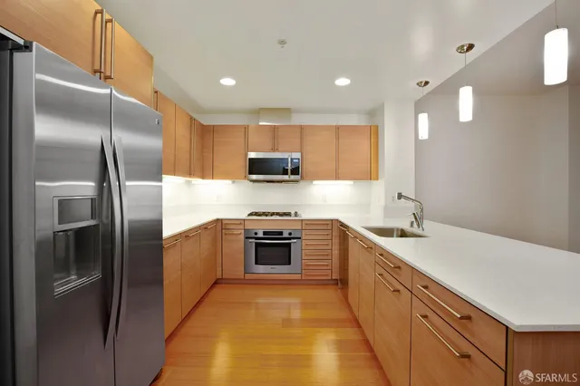 a kitchen with stainless steel appliances granite countertop a refrigerator a sink a stove and oven