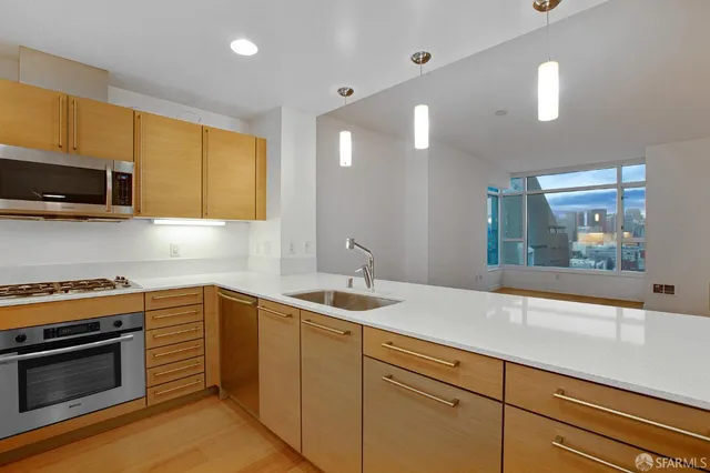 a kitchen with stainless steel appliances granite countertop a sink a stove and a wooden floors