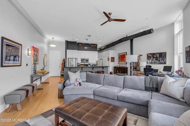 a living room with furniture kitchen view and a wooden floor