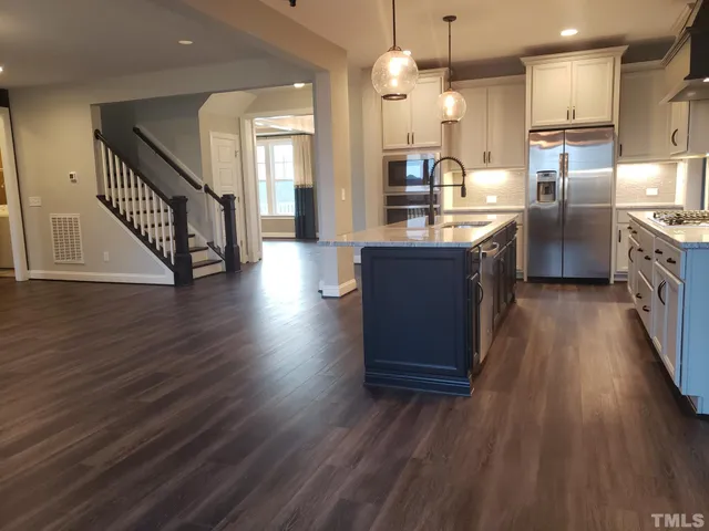 a kitchen with stainless steel appliances granite countertop a sink a stove and a wooden floors
