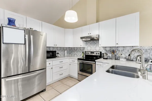 a kitchen with granite countertop a refrigerator stove top oven and sink