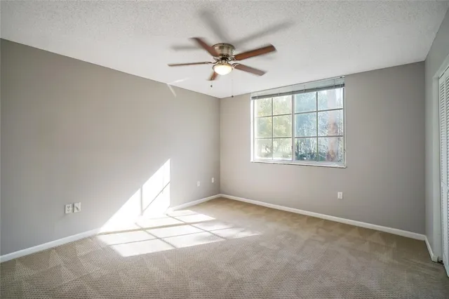 an empty room with windows and ceiling fan