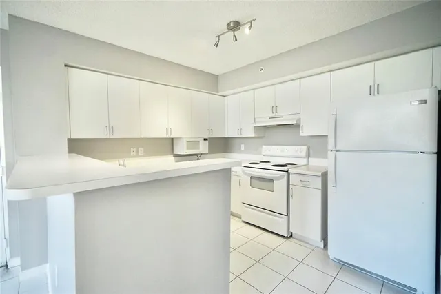 a kitchen with a sink a refrigerator and white cabinets