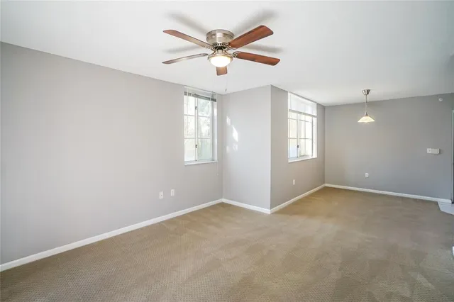 an empty room with windows and ceiling fan
