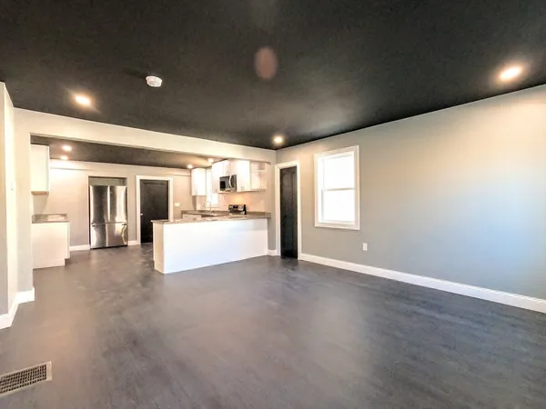 a view of a big room with wooden floor and a kitchen