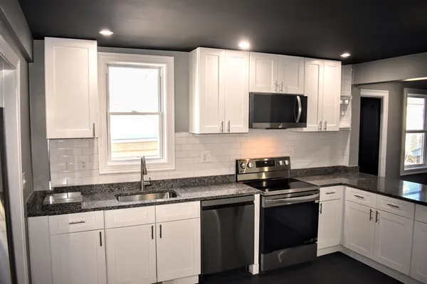 a kitchen with granite countertop a sink a window and appliances