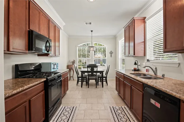 a kitchen with granite countertop a sink stove and cabinets