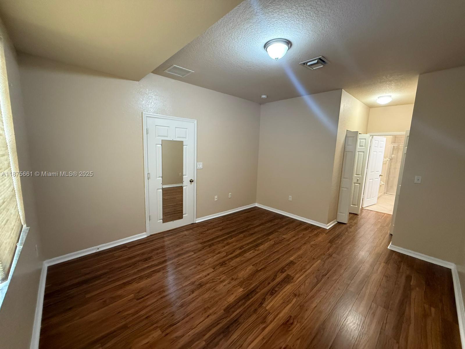 13218 Southwest 44th Street, Unit 11106 Miramar, FL 33027 - Photo 6 of 23 a view of an empty room with wooden floor and a window