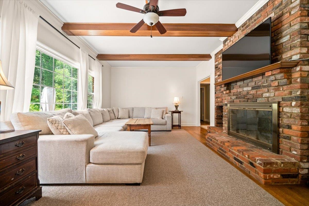 1273 Brookfield Road Memphis, TN 38119 - Photo 12 of 40 Spacious room featuring a brick fireplace with a wood mantel, exposed wood ceiling beams, wet bar, a ceiling fan, and large windows
