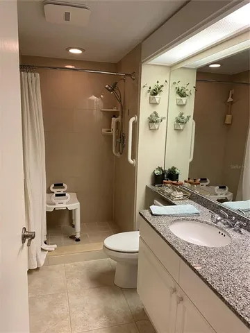 a bathroom with a granite countertop sink a toilet a mirror and shower