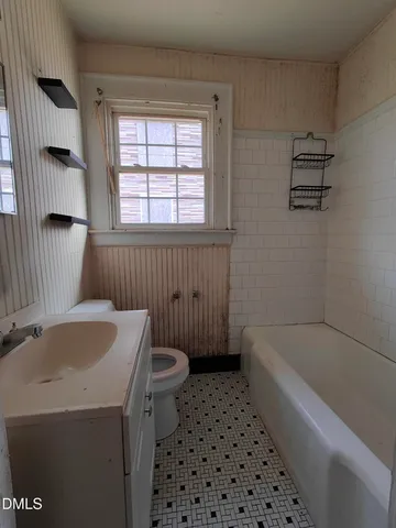 a bathroom with a sink a toilet a window a vanity and shower