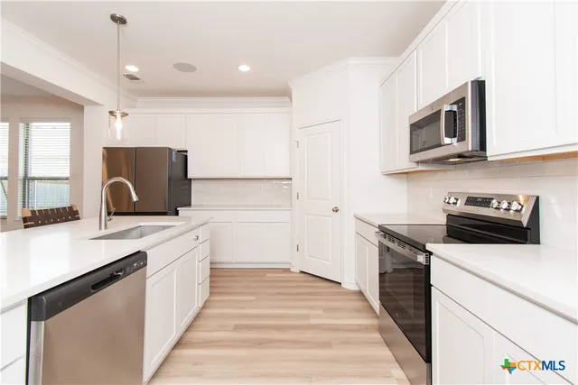 a kitchen with stainless steel appliances a stove microwave and sink