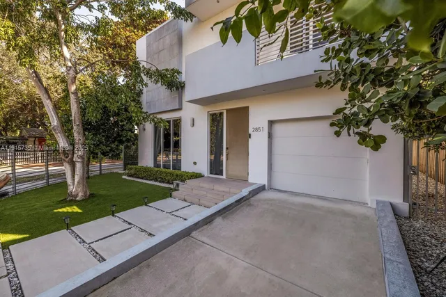 front view of a house with a yard and an trees