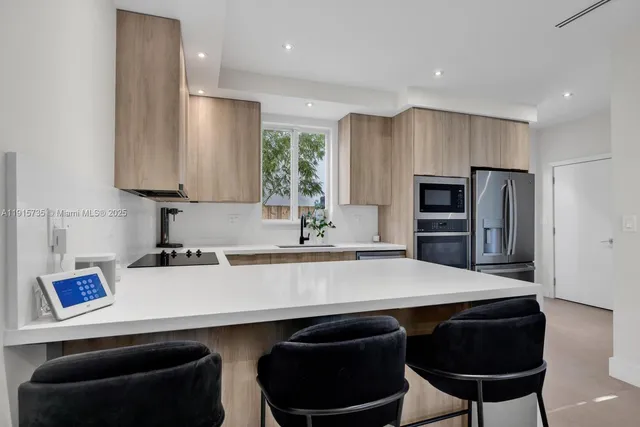 a kitchen with stainless steel appliances a sink dishwasher and a refrigerator with wooden floor