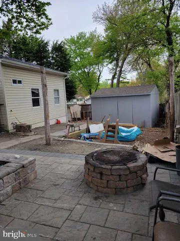 a view of a backyard with table and chairs potted plants and a large tree