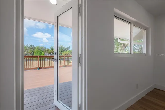 an empty room with wooden floor chandelier and windows