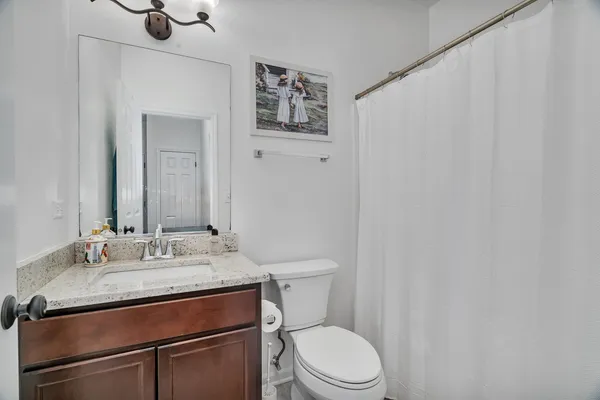 a bathroom with a granite countertop sink mirror vanity and toilet