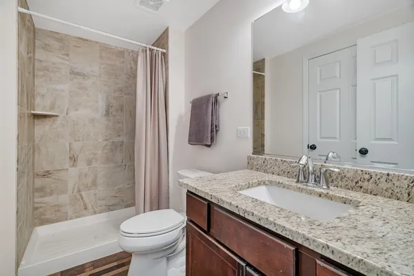 a bathroom with a granite countertop sink toilet and shower
