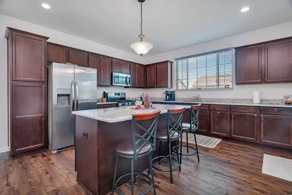 a kitchen with stainless steel appliances granite countertop a refrigerator a sink dishwasher a stove and white countertops with wooden floor