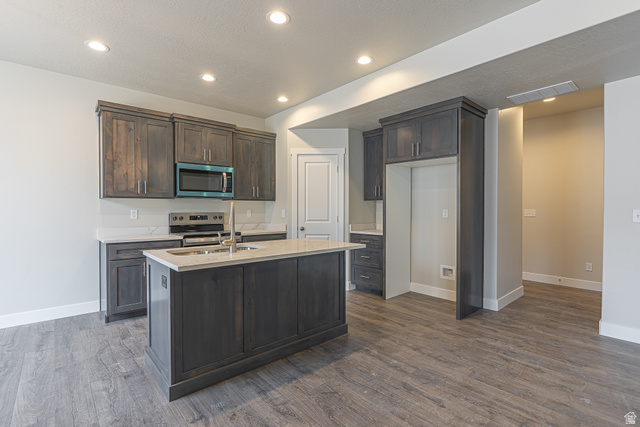 2249 South 1090 West, Unit 76 Nibley, UT 84321 - Photo 3 of 19 Modern kitchen featuring dark wood-finish cabinetry, light countertops, and a central island with an undermount sink