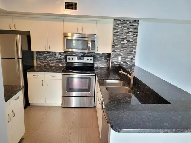 a kitchen with granite countertop a sink and stainless steel appliances