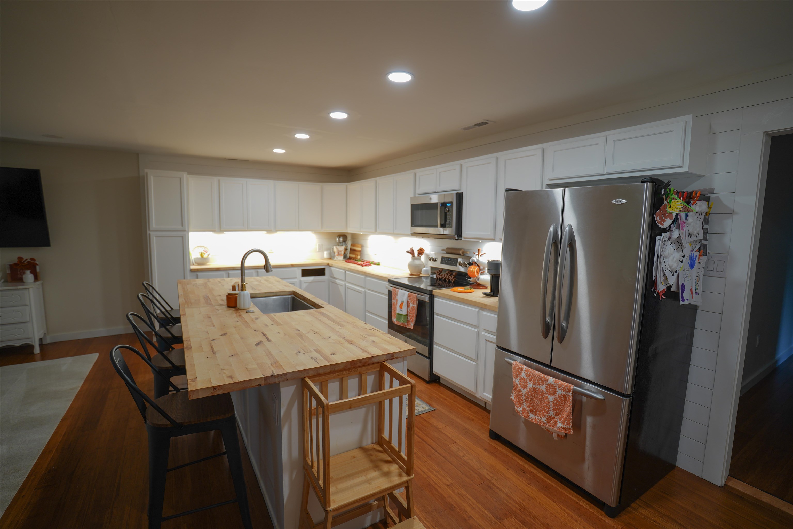 Kitchen featuring white shaker cabinetry, wood-finish countertops, stainless steel appliances, recessed lighting, and a wood-finish island with an undermount sink