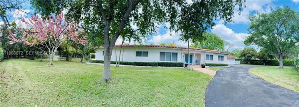 a front view of a house with a yard and fountain in middle