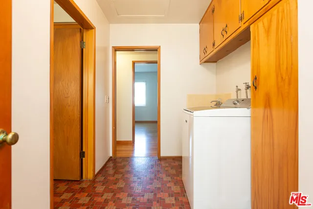 a bedroom with a bed next to a window with workspace
