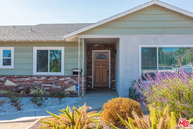 a front view of a house with a large window and potted plant