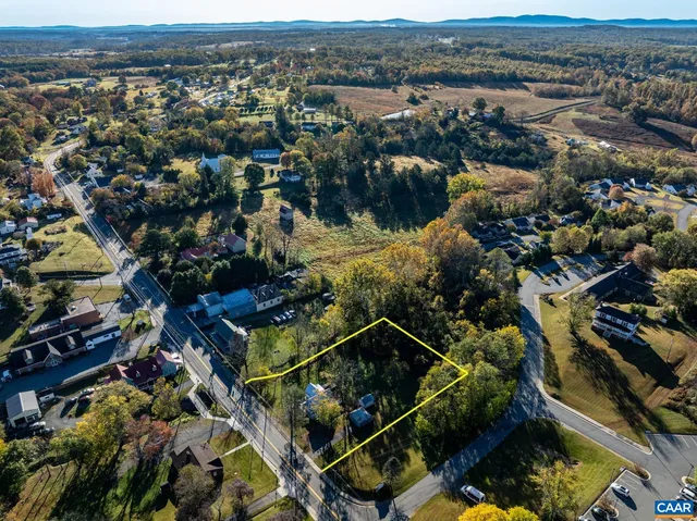 an aerial view of residential house with parking and trees