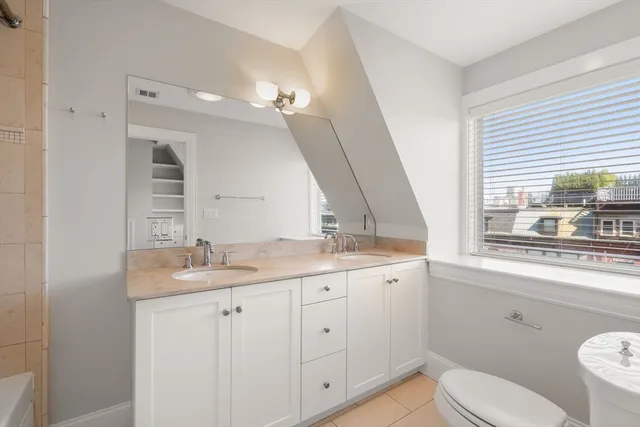 a bathroom with a granite countertop sink a large mirror a toilet and a window