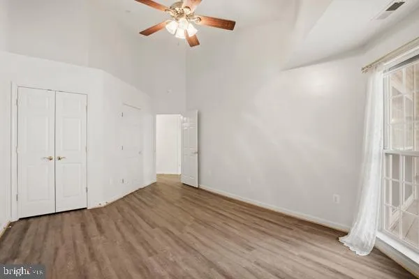 an empty room with wooden floor closet and windows