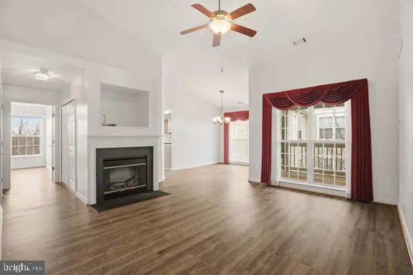 a view of a livingroom with a fireplace a ceiling fan and wooden floor