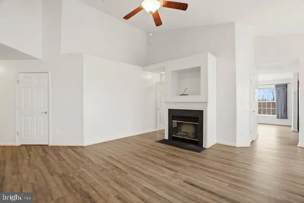 a view of an empty room with wooden floor fireplace and a window