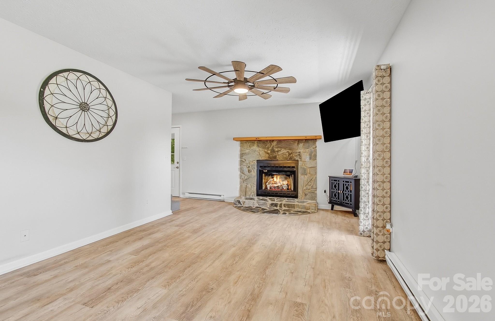 2131 Coleman Mountain Road Waynesville, NC 28785 - Photo 4 of 40 a view of a livingroom with a fireplace a chandelier fan and wooden floor