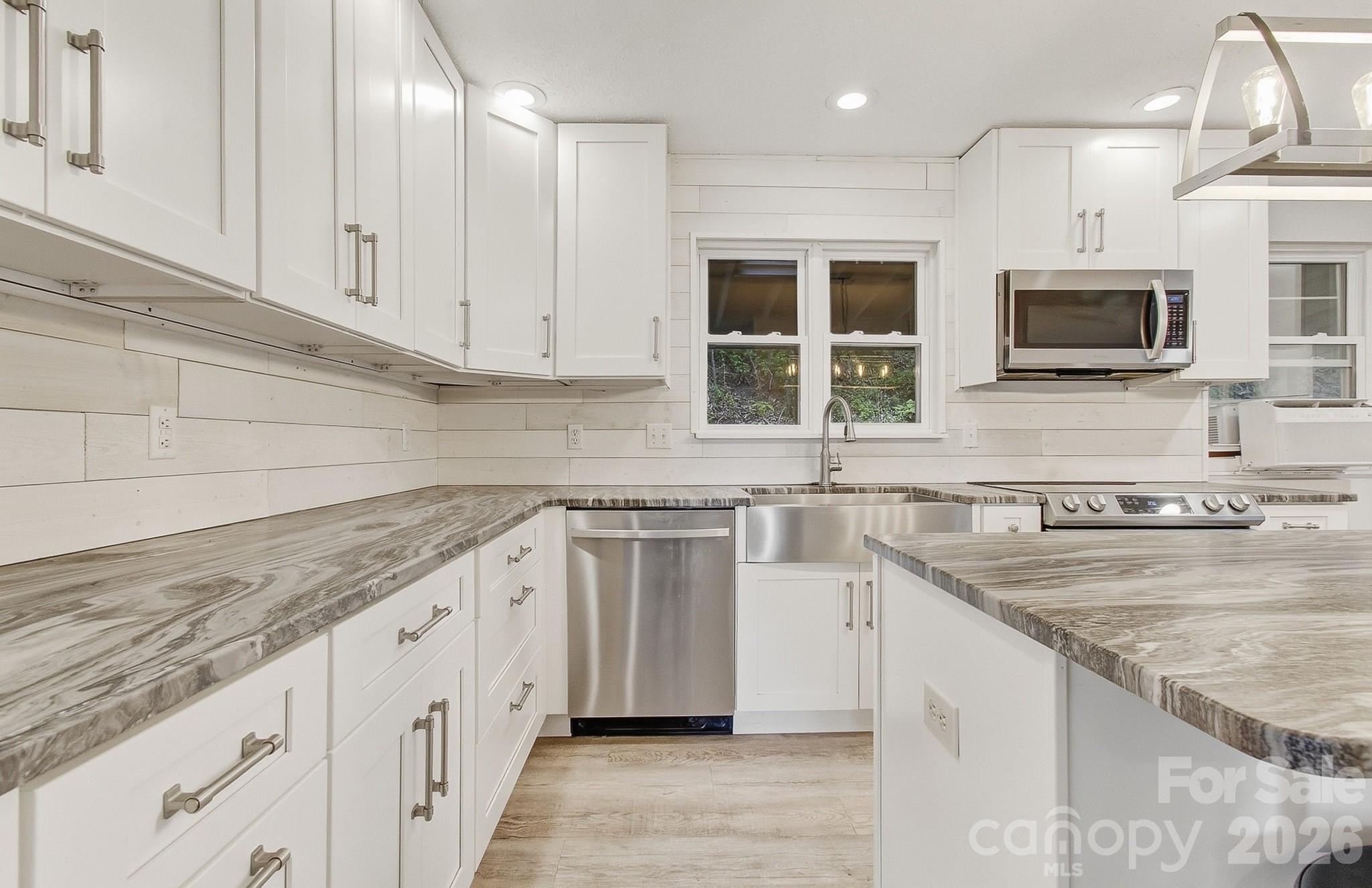 2131 Coleman Mountain Road Waynesville, NC 28785 - Photo 7 of 40 a kitchen with stainless steel appliances granite countertop a sink and a stove