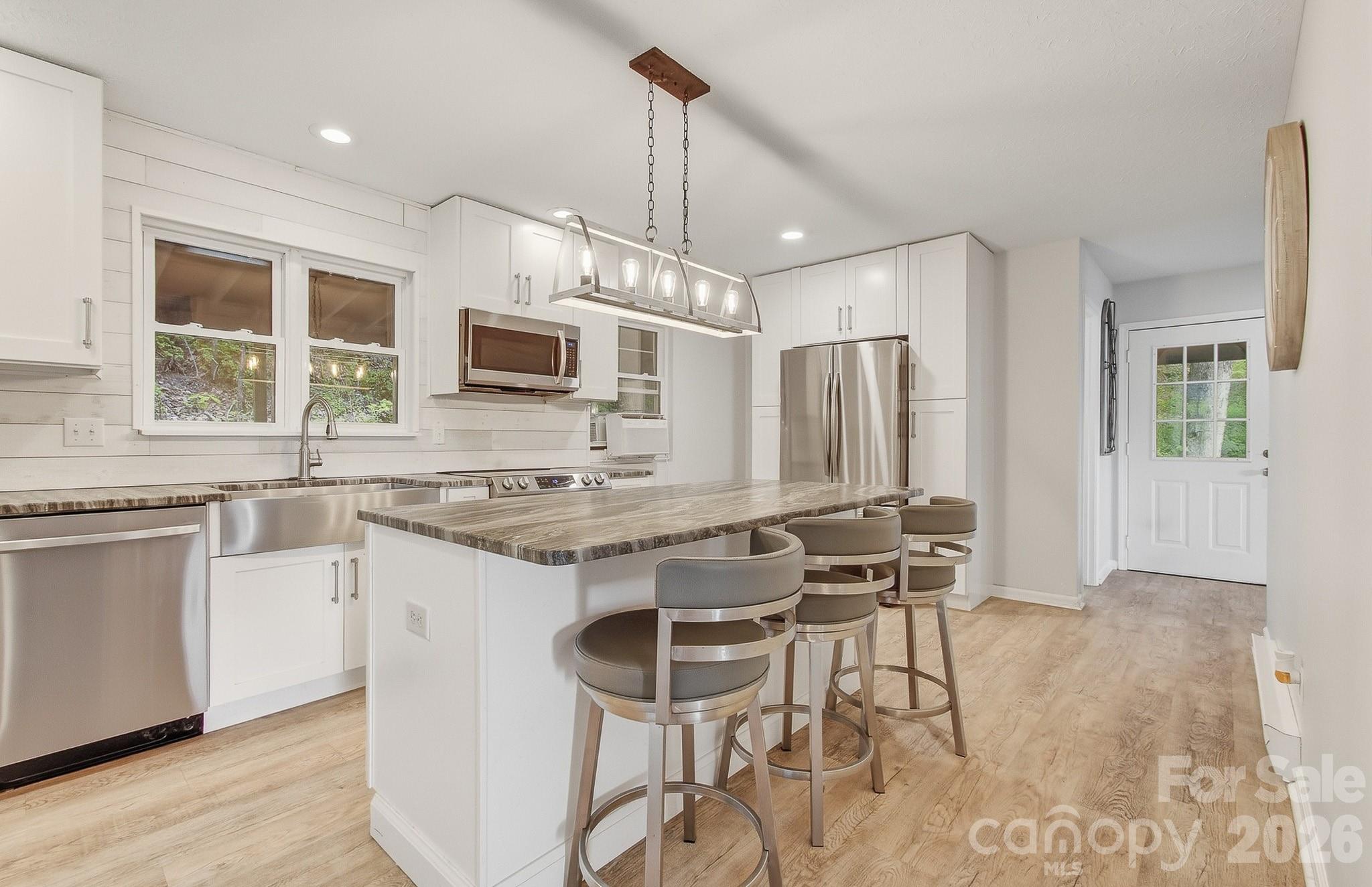 2131 Coleman Mountain Road Waynesville, NC 28785 - Photo 9 of 40 a open kitchen with stainless steel appliances granite countertop a stove top oven a sink dishwasher a dining table and chairs with wooden floor