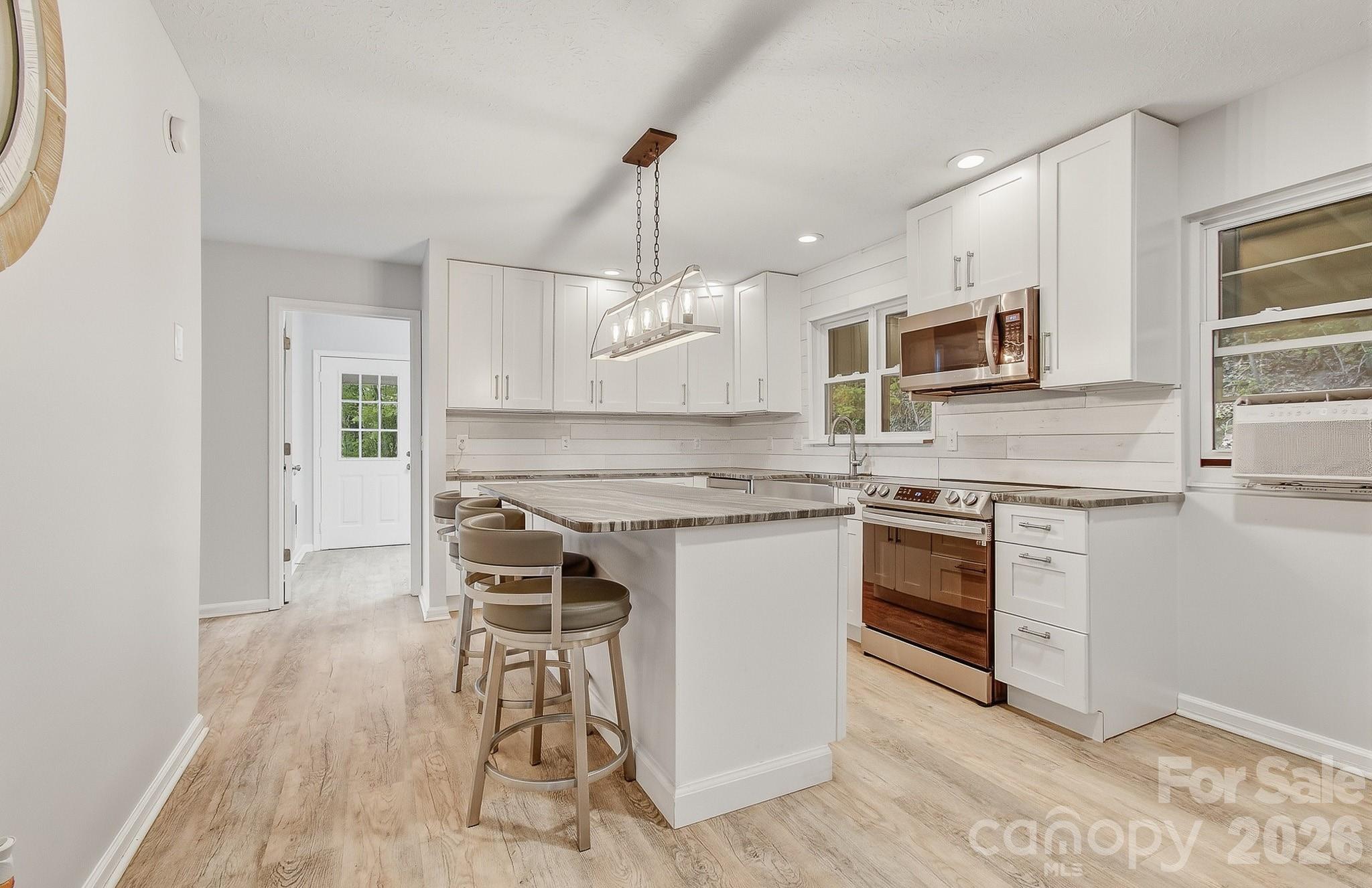 2131 Coleman Mountain Road Waynesville, NC 28785 - Photo 10 of 40 a kitchen with kitchen island granite countertop a stove a sink and a microwave