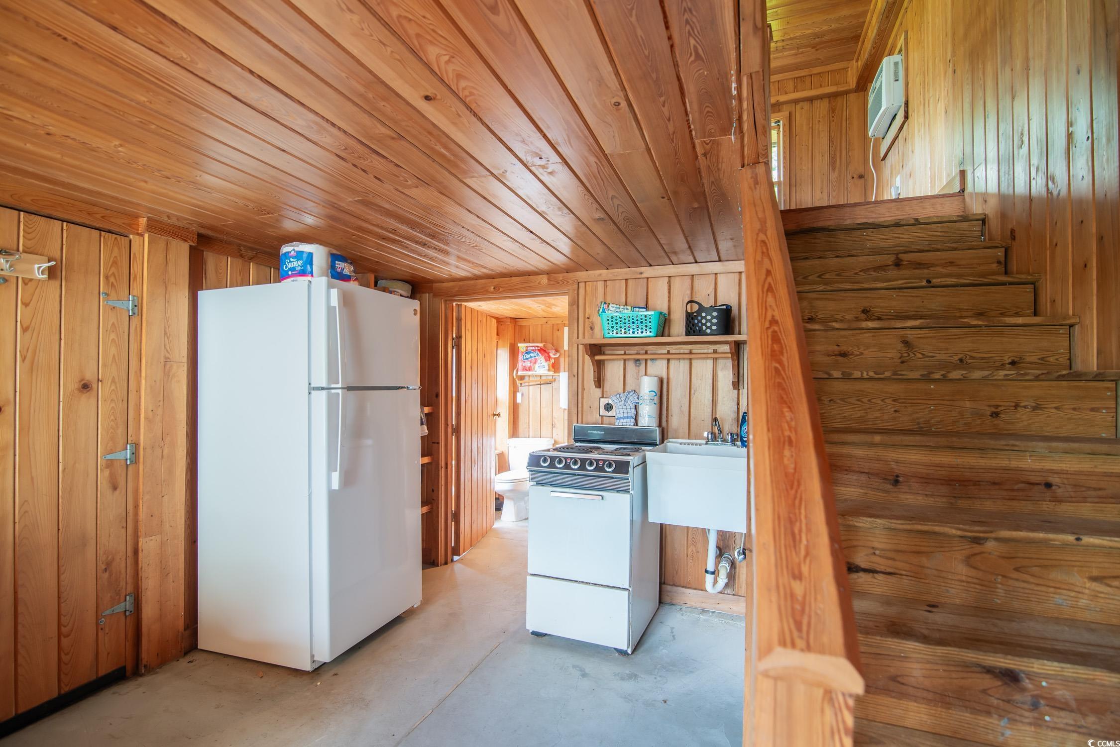 127 Brown Pelican Loop Pawleys Island, SC 29585 - Photo 9 of 31 Kitchen featuring white appliances, wooden walls, concrete floors, and wooden ceiling