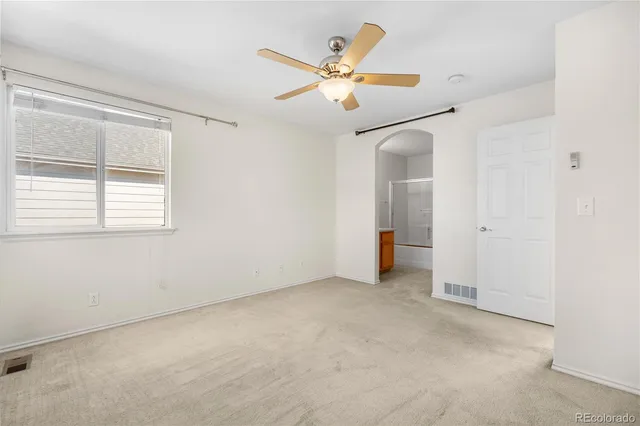 an empty room with closet and a ceiling fan