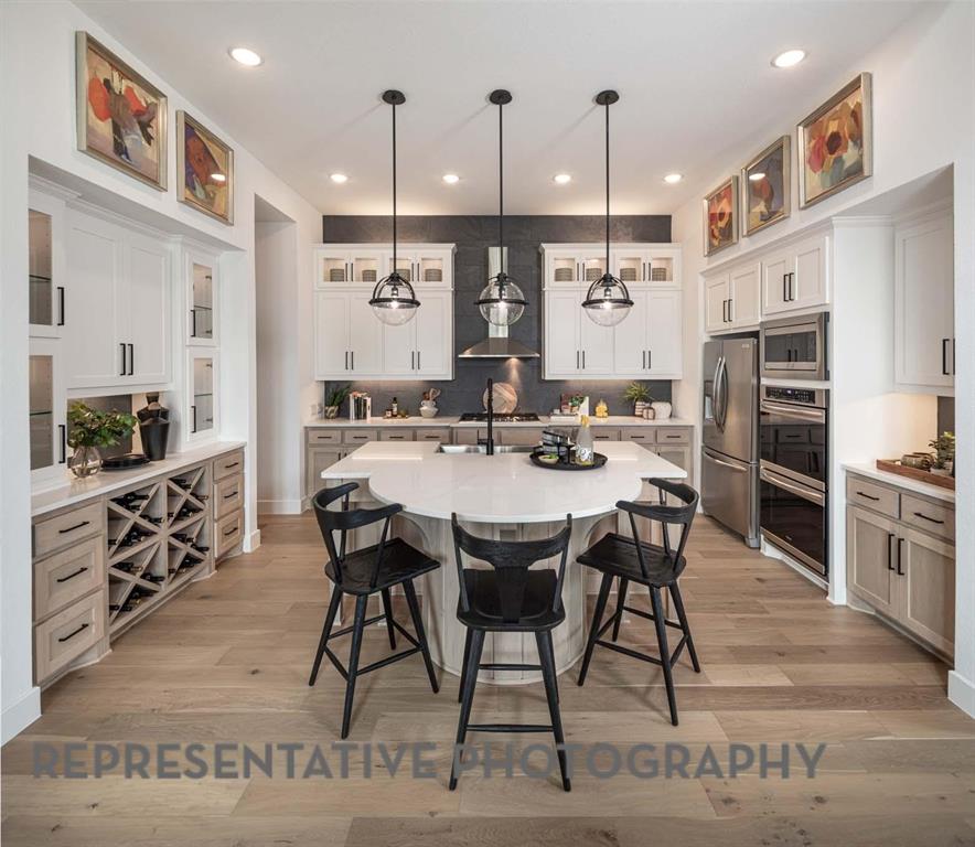 930 Heatherbrook Drive Prosper, TX 75078 - Photo 4 of 37 a kitchen with stainless steel appliances kitchen island granite countertop a table chairs sink and cabinets